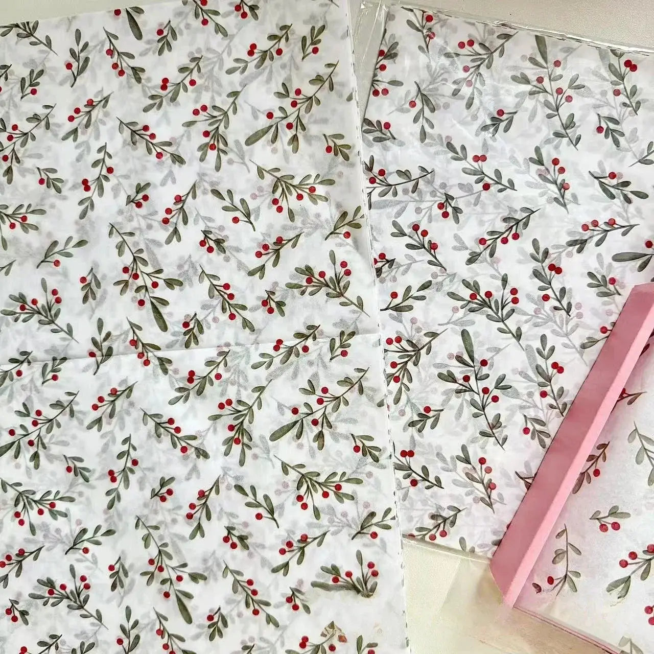 Gift wrap paper sheets with holly berry pattern, wax-coated, white background with green leaves and red berries