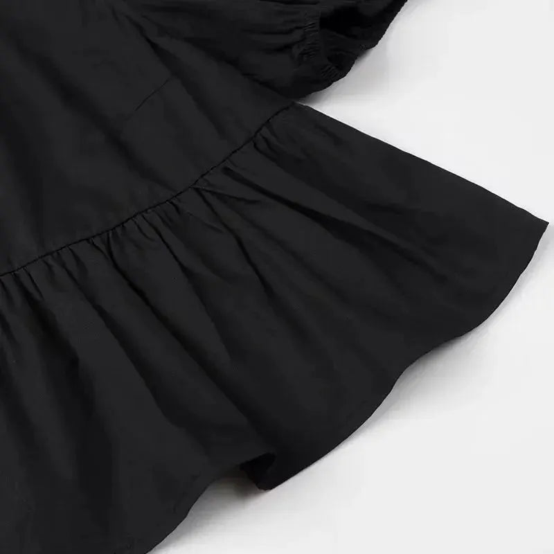 Women's black puff-sleeve blouse with tiered ruffle hem, close-up detail