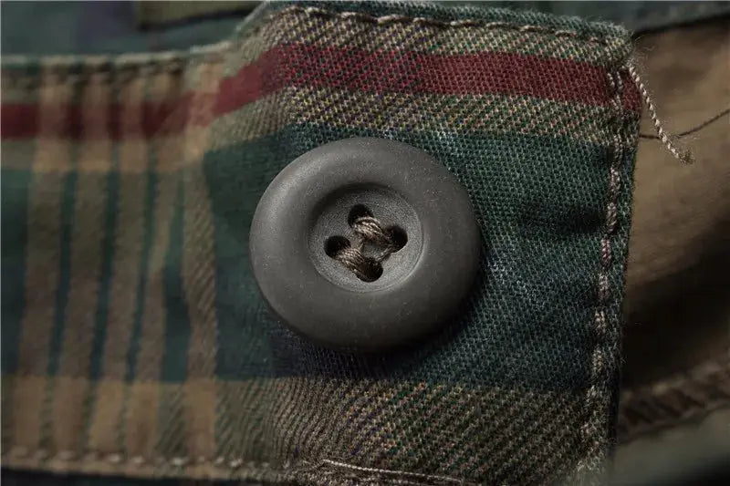 Men's plaid shorts close-up with a dark button on green-blue plaid fabric