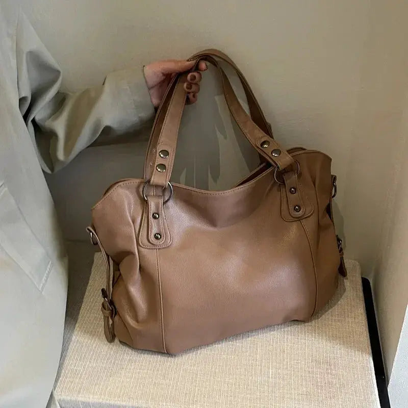 Soft interior compartment shoulder bag in tan PU leather with dual top handles and metal hardware