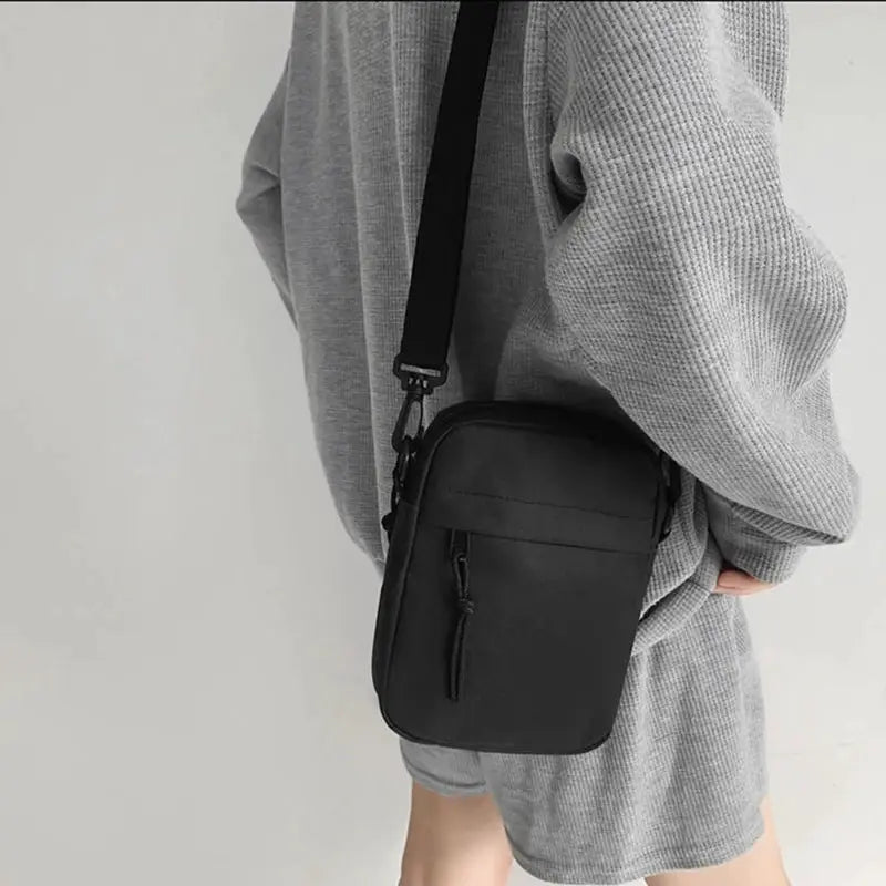 Simples Market black compact crossbody bag with single-shoulder strap and front zipper pocket