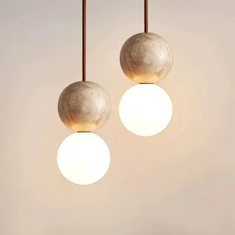 Led pendant light pair with cream stone spheres and frosted white globe bulbs on long hanging cables.
