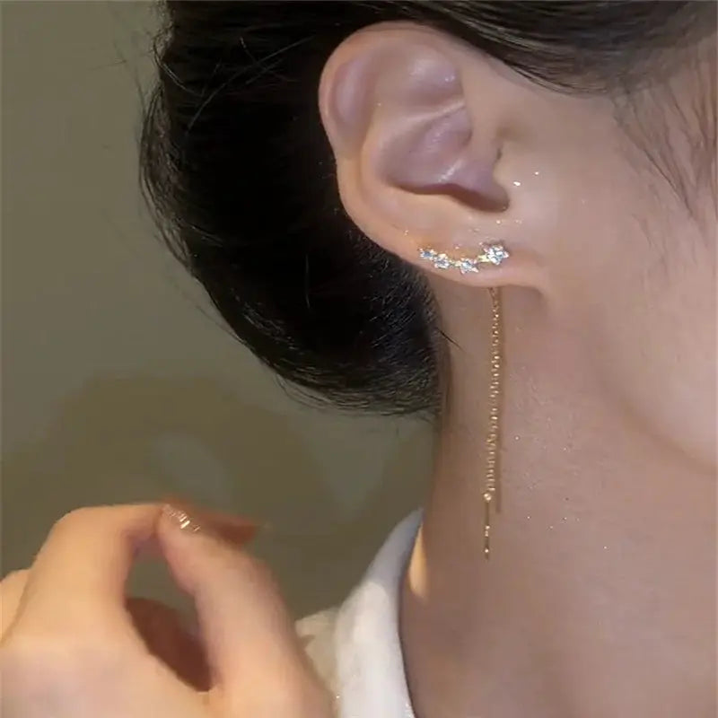 Gold-tone long wire tassel drop earrings with star/heart bead accents on ear