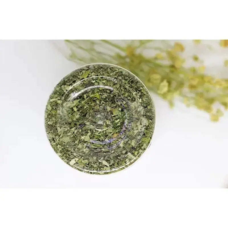 Catnip herb in a glass bowl, organic green leaves, top view.