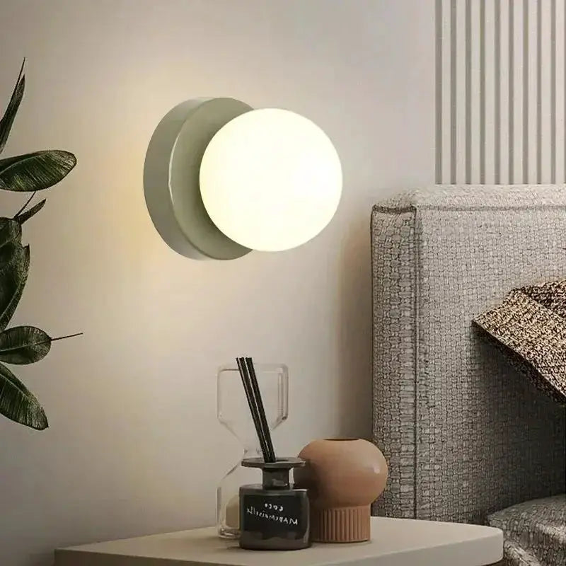 Nordic Macaron LED wall lamp 10cm glass sconce in white, wall-mounted beside a bed.