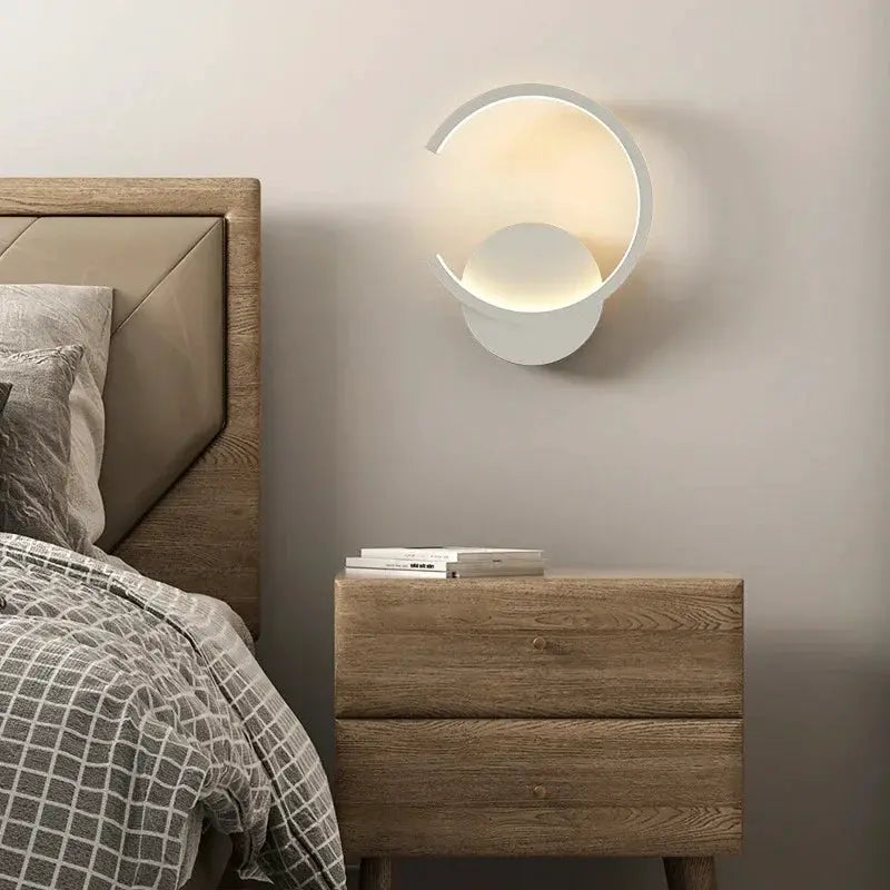 Modern LED wall lamp with white circular arc design and warm glow above a wooden nightstand