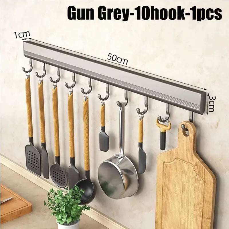 Wall-mounted aluminum kitchen utensil rack by Simples Market with multiple hooks and a cutting board.