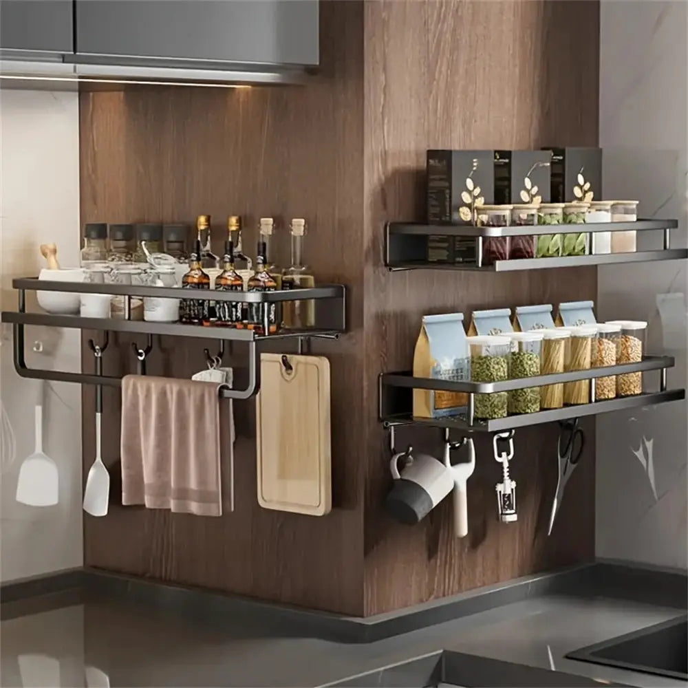 Two black metal wall-mounted storage racks with a hanging rod and hooks for spices, jars, towels, and utensils