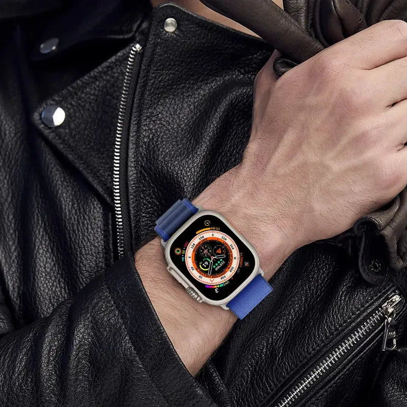 Apple Watch on wrist with blue strap and metal case, showcasing watch face