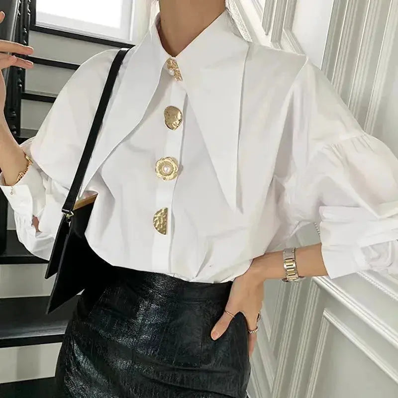 White women's blouse with sharp collar, loose fit, puff sleeves, and gold buttons