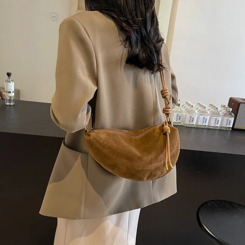 Faux suede shoulder bag in brown, curved dumpling crossbody with knotted strap.