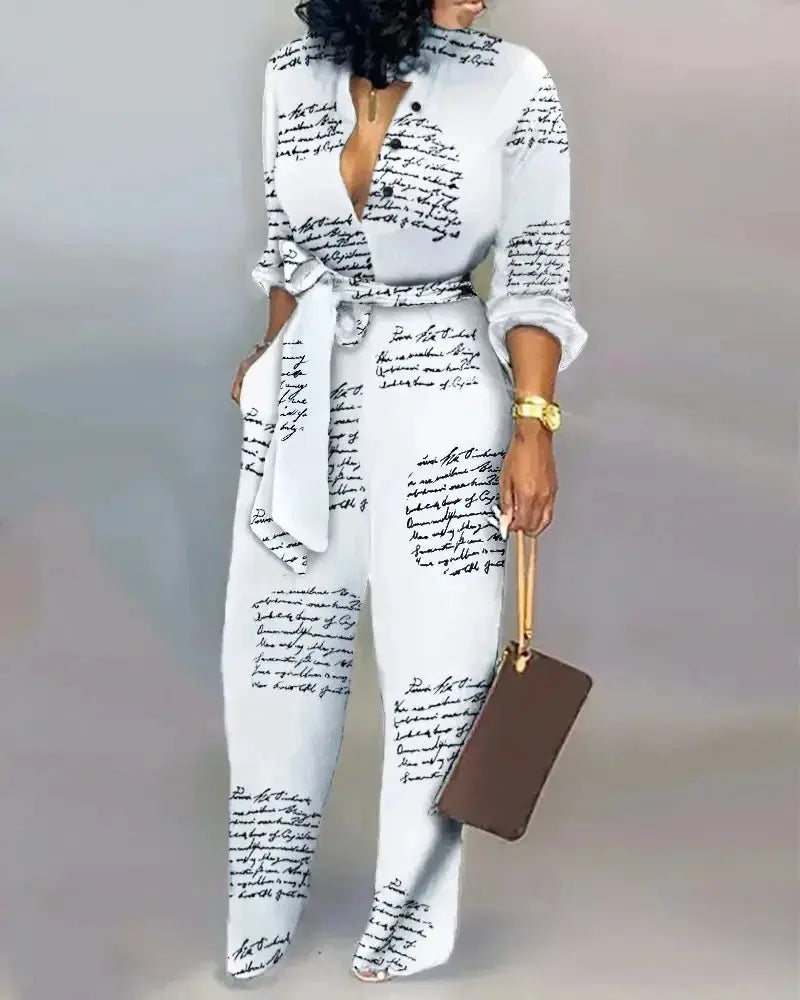 Jumpsuit by Simples Market, white with black handwritten script, belted waist, long sleeves.