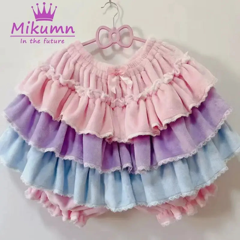 Pastel layered ruffle shorts in pink, lilac, and blue with lace trim; Mikumm logo visible