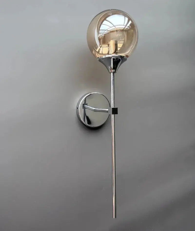 Modern glass wall lamp sconce with a golden globe and chrome wall mount.