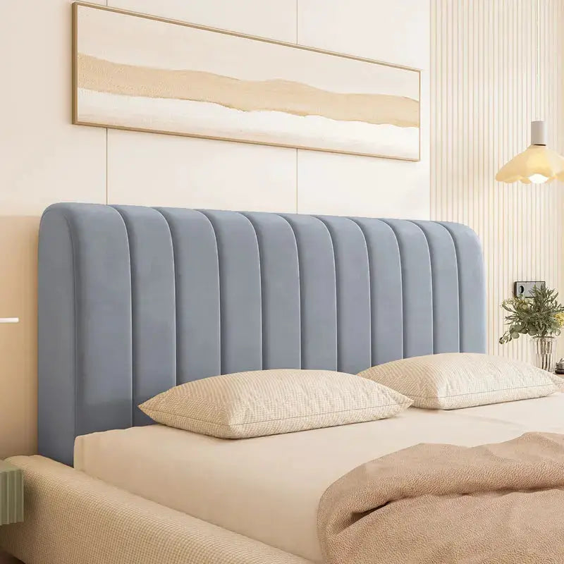 Bed headboard cover in blue velvet with padded vertical channels on a neatly made bed