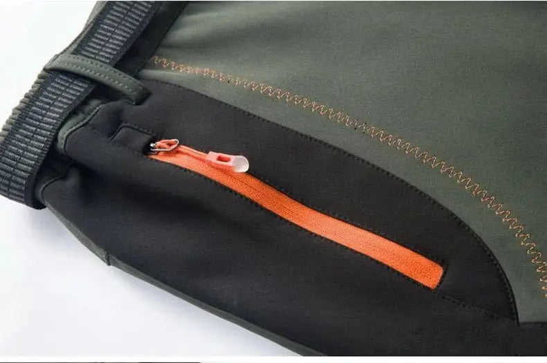 JNLN Thick Warm Fleece Hiking Pants for men, soft-shell rain trousers with orange zipper pocket on green/black panels.