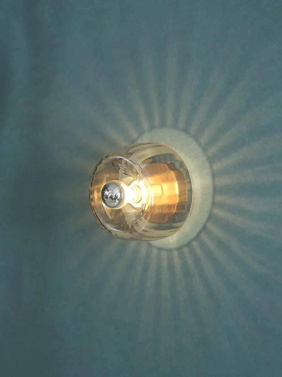 LED Bauhaus glass wall lamp with clear globe and chrome detail, warm glow on blue wall