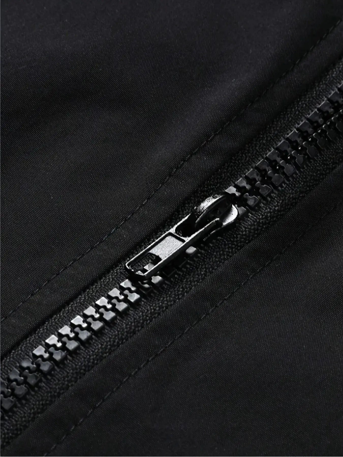 Men's lightweight jacket zipper close-up on black fabric.