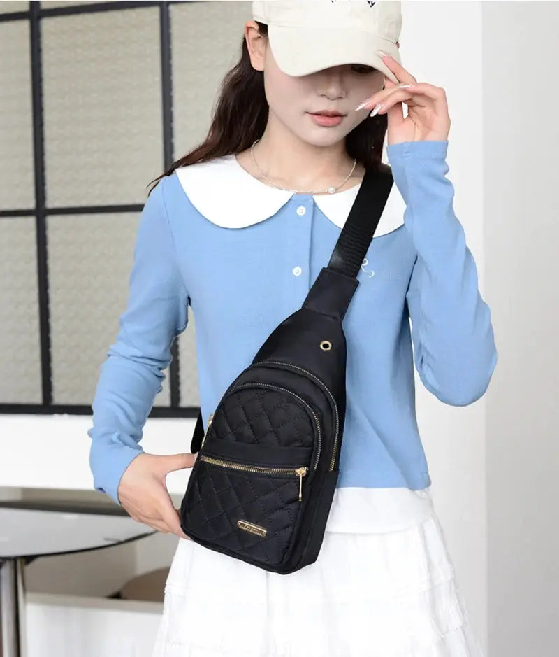 Crossbody chest bag: black quilted with gold zippers, worn by a model in a light blue top.