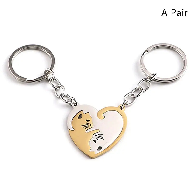 Pair of cute cat-hug keychains with a two-tone stainless steel heart pendant in gold and silver.