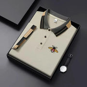 Simples Market beige polo with bee embroidery, gray striped collar, 3-button placket; boxed with wristwatch.