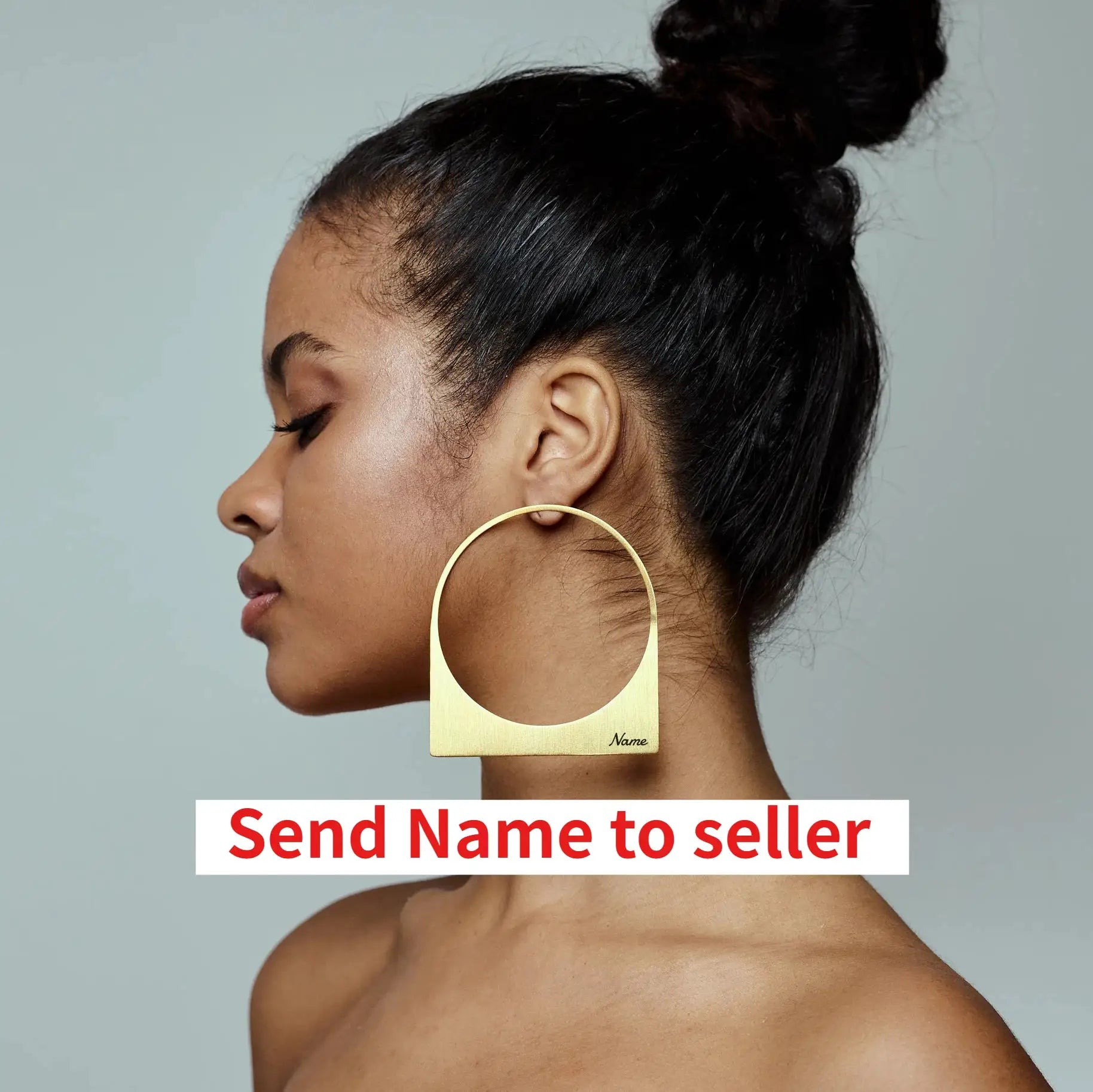 African large hoop earring with gold-tone name plate, worn by a woman.
