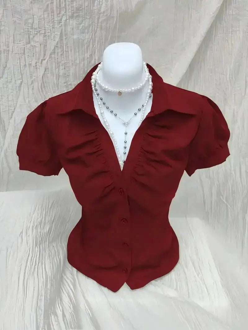 Women's red short-sleeve ruched-front button-down blouse on a mannequin with layered pearl necklaces