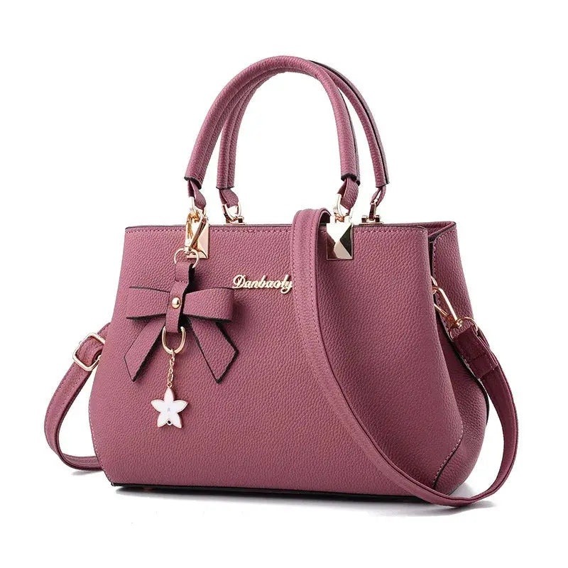 Bow handbag in pink with top handles and shoulder strap, Danbao logo, gold hardware, flower charm.