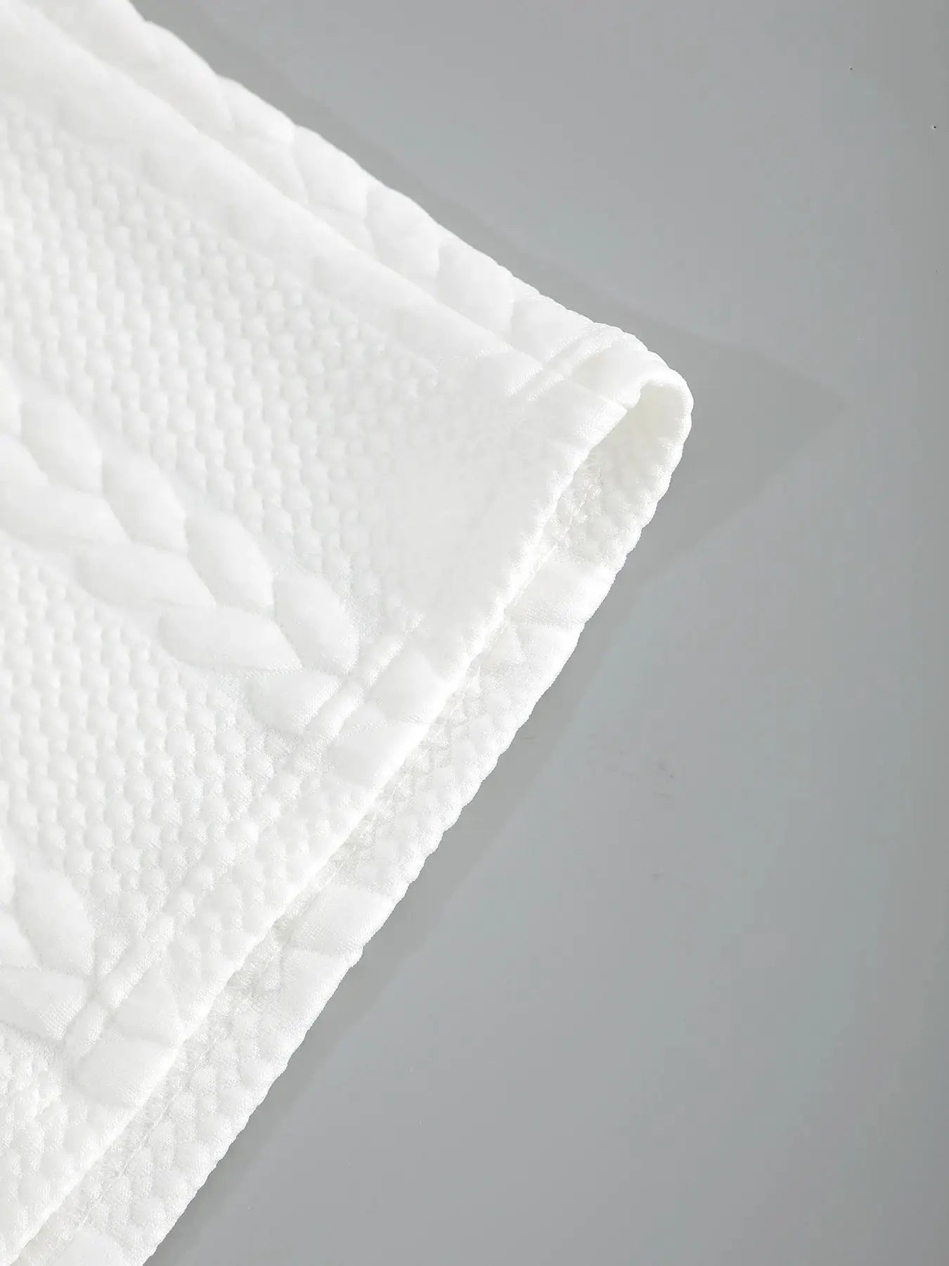 Men's white drawstring shorts fabric close-up with quilted textured weave and stitched edge