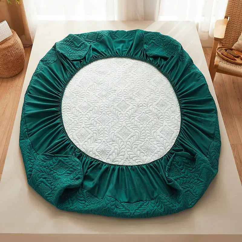 Waterproof quilted round mattress protector in emerald green with elastic fitted edge