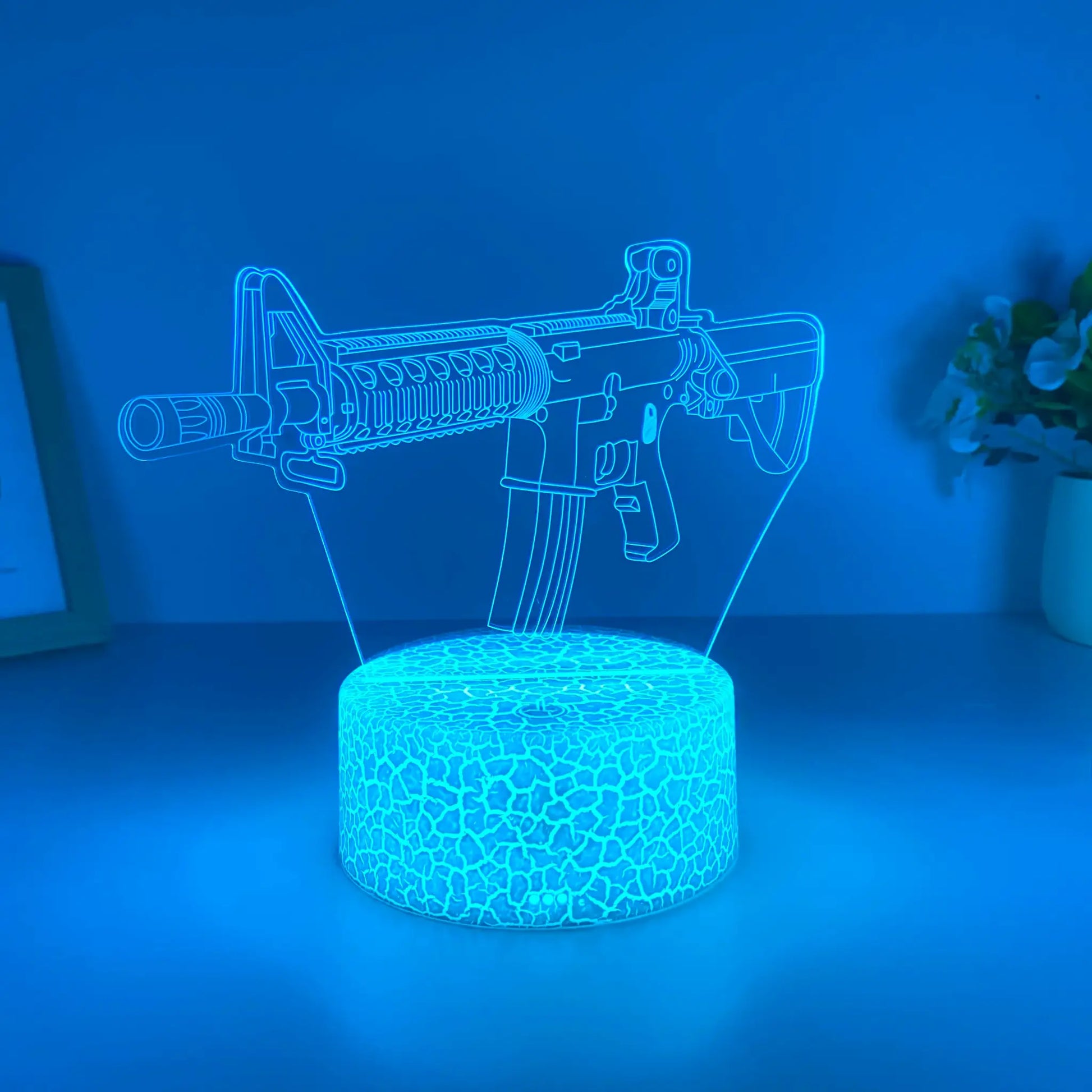 Blue acrylic 3D gun night light on a patterned circular base; USB powered desk lamp.