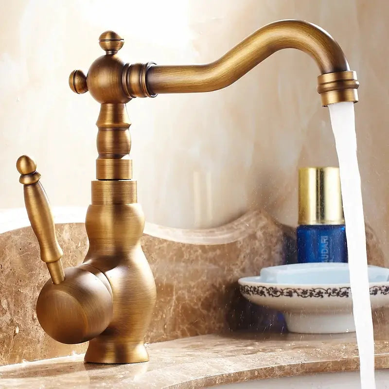 Antique brass bathroom faucet with rotating spout and lever handle on marble sink.