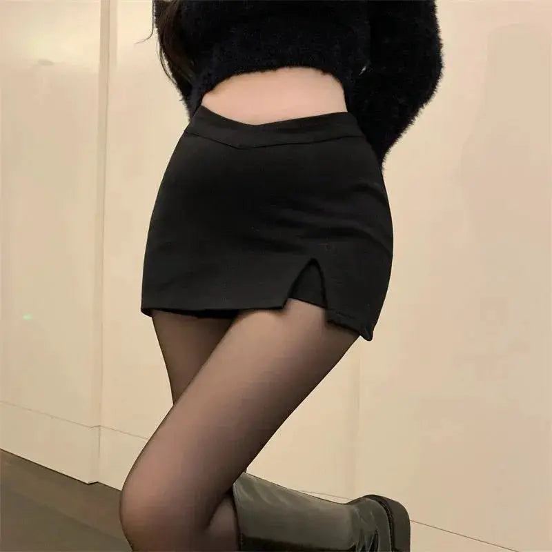 Black split mini skirt with high waist and front slit, worn with sheer tights and boots.