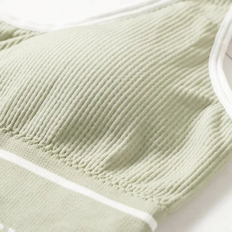 Simples Market women's seamless ribbed sports bra top in pale green with white trim.