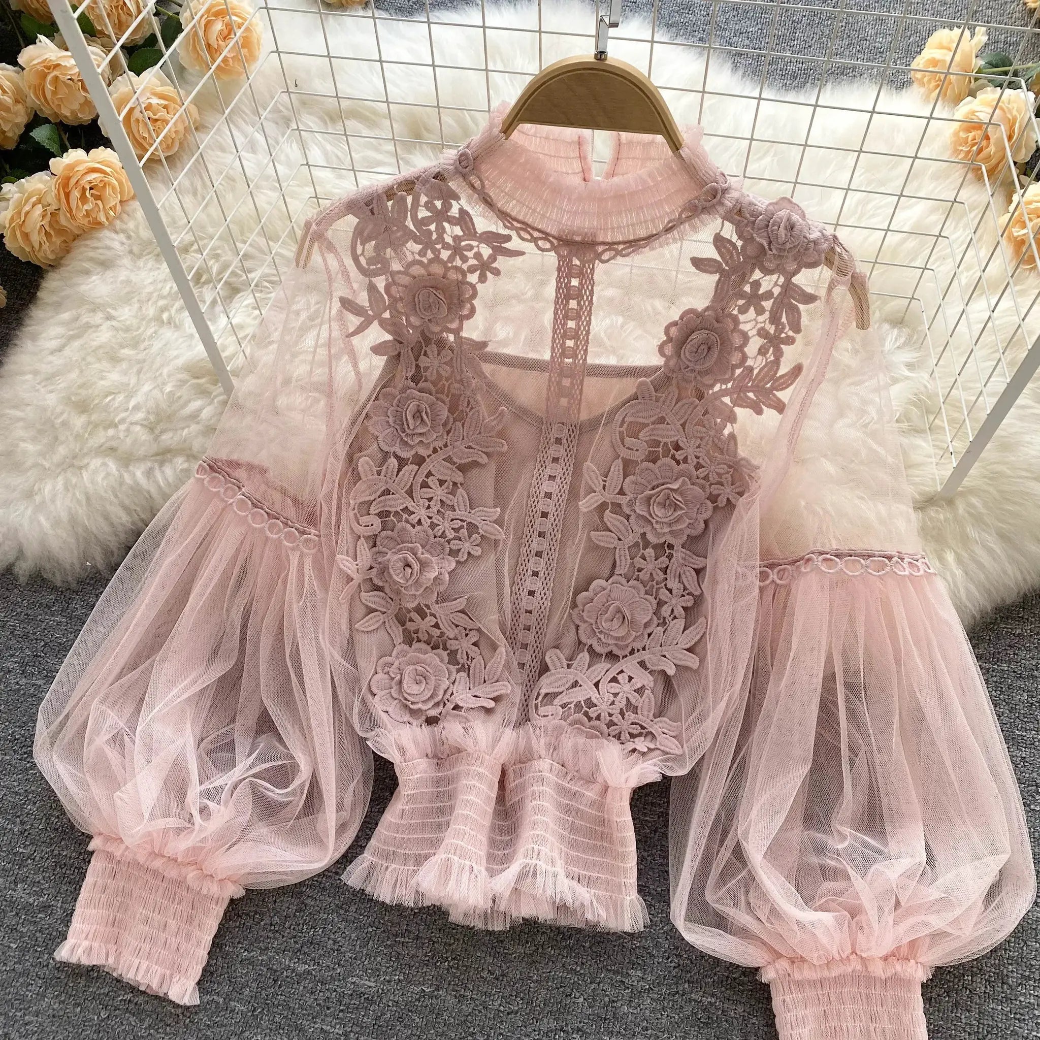 Pink lace puff-sleeve blouse with floral embroidery and sheer mesh fabric on a hanger
