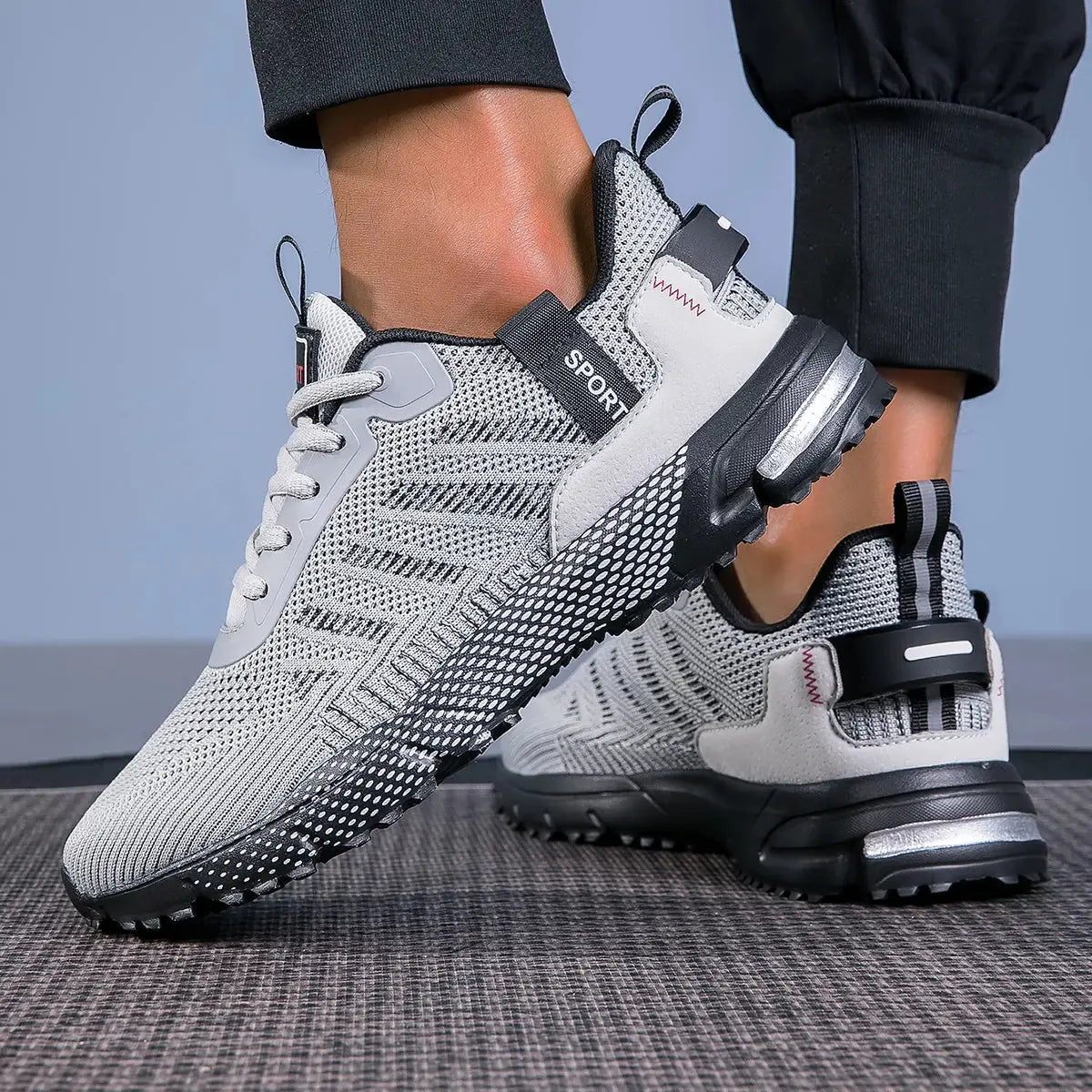 Men's running shoes with gray knit upper and black sole, two sneakers displayed.