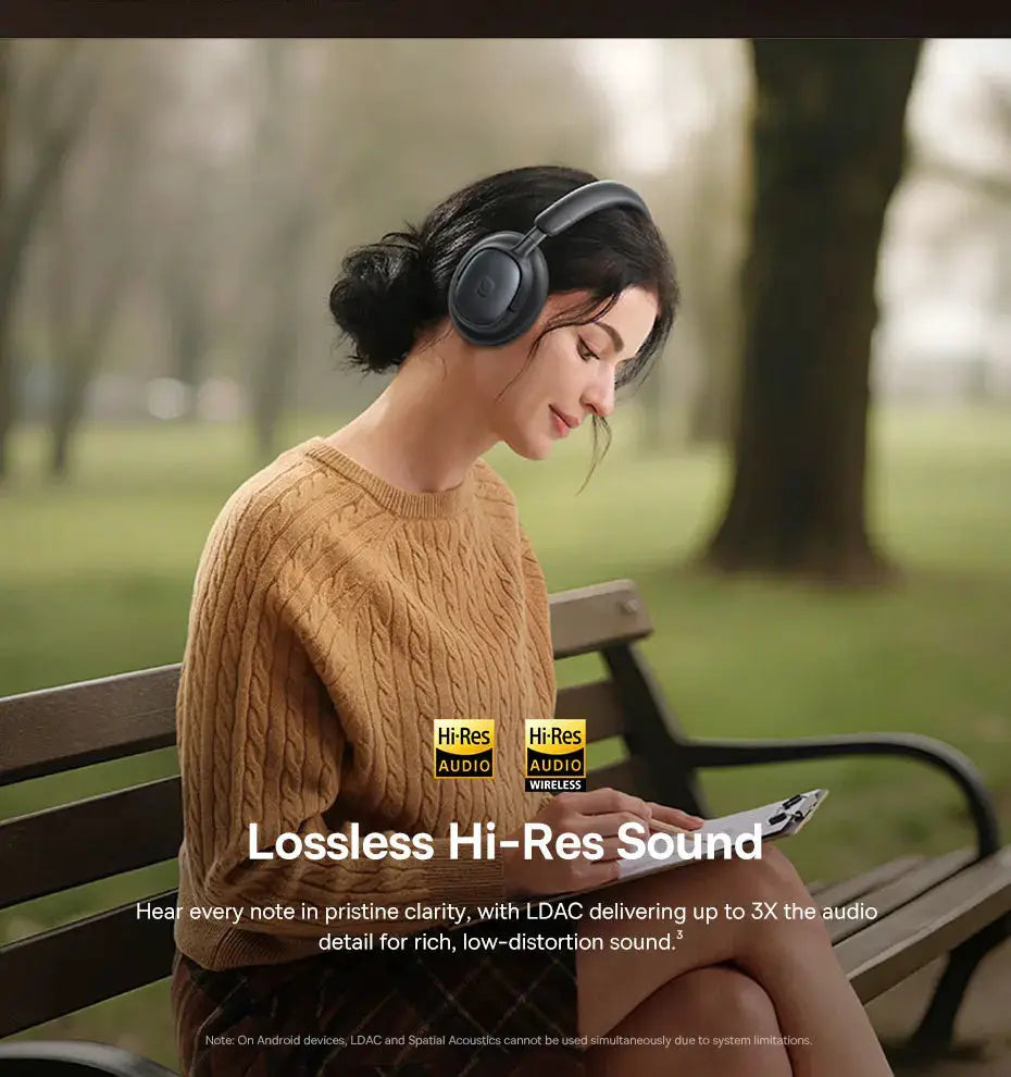 Baseus Bowie MH1 Bluetooth over-ear headphones in black, wireless, worn by a woman on a park bench