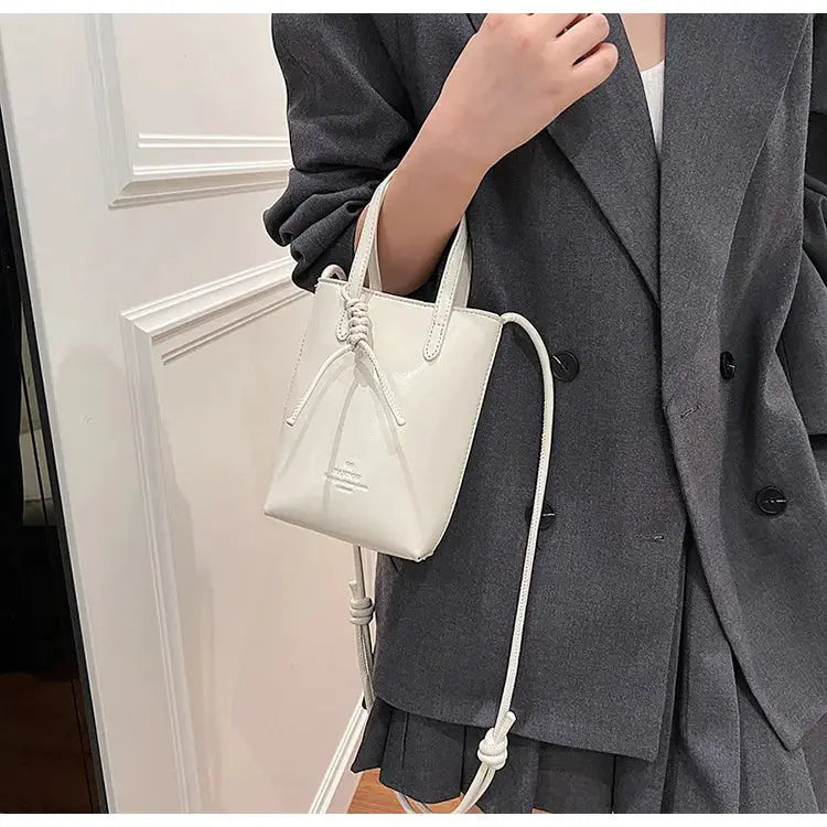 PU leather white mini crossbody bag with dual top handles and long adjustable strap, tassel accent.