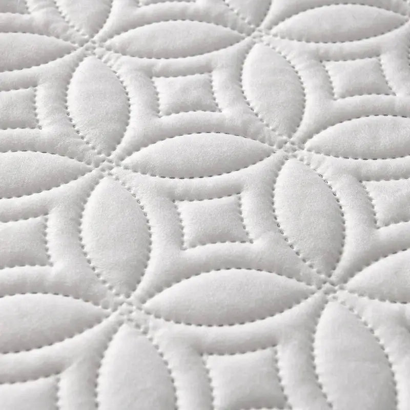 Quilted white mattress protector with a circular pattern and breathable fabric