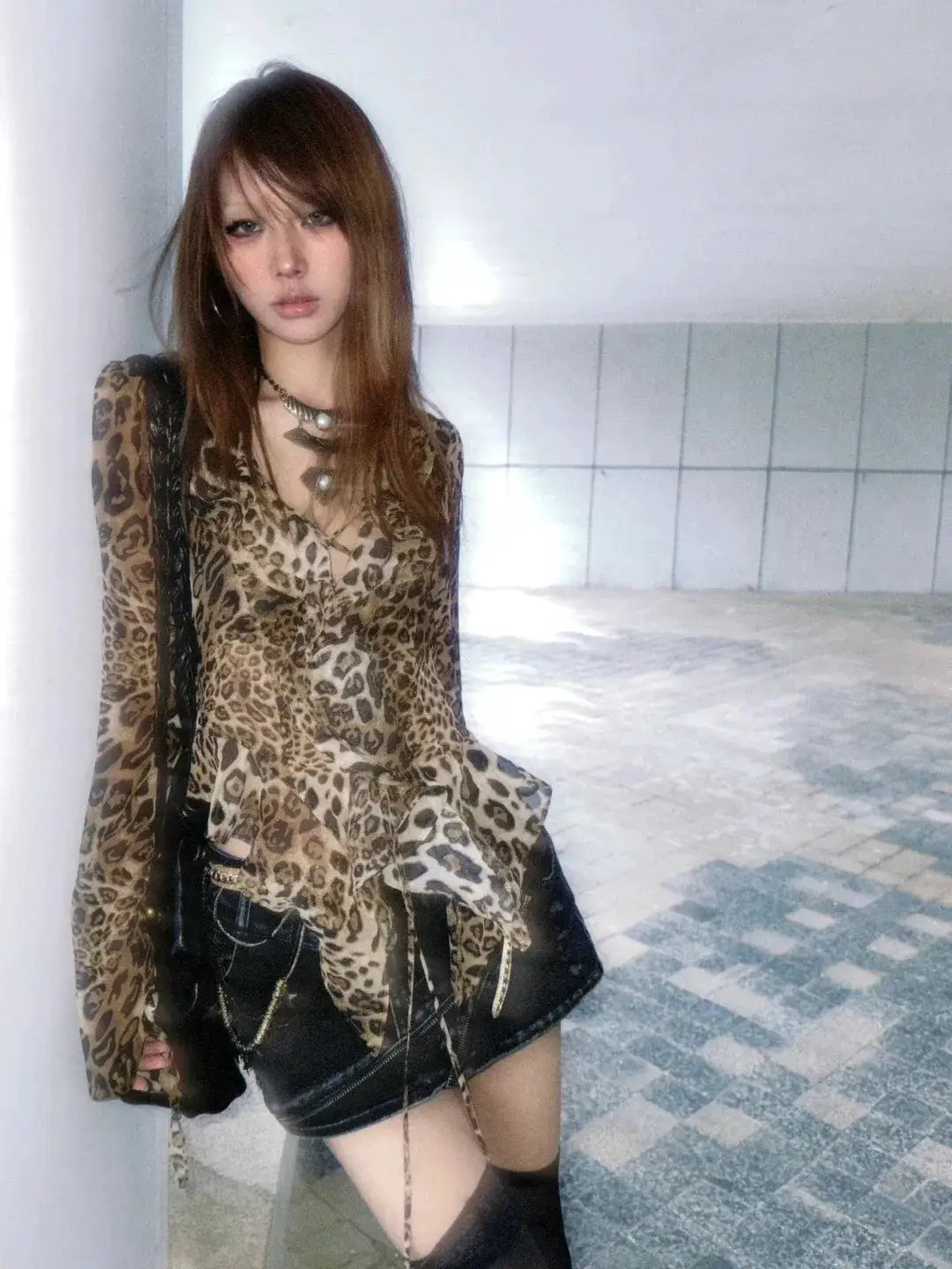 Leopard print sheer V-neck blouse with ruffles, worn with a black leather mini skirt and thigh-high socks.