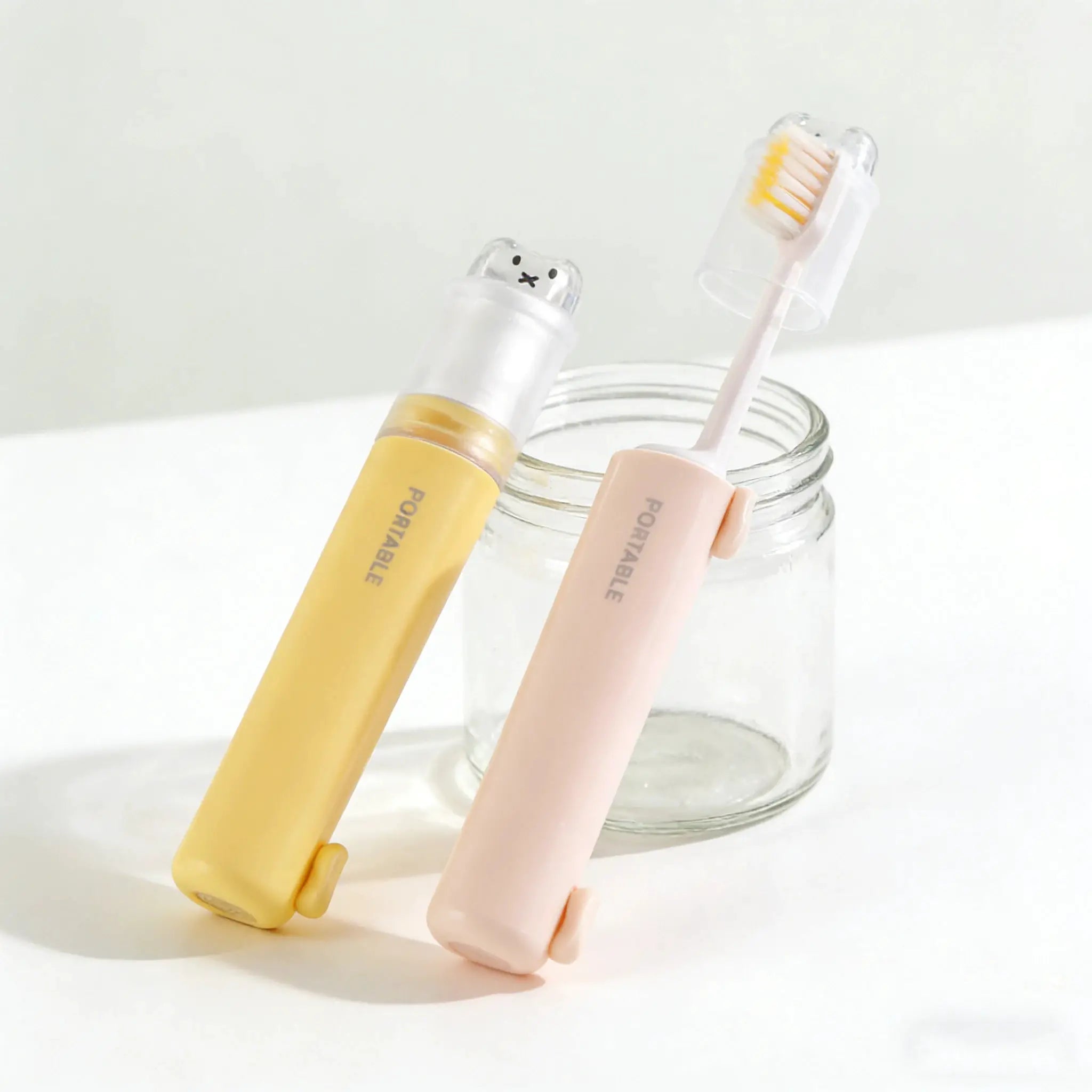 Simples Market 2-in-1 foldable travel toothbrushes with bear dust covers in pastel yellow and pink