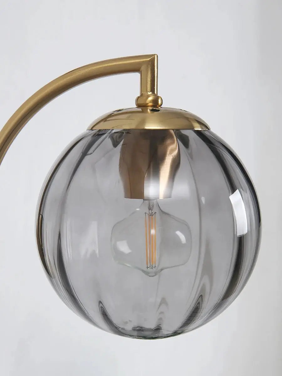 Modern LED wall lamp with a smoked glass globe and brass arc arm, minimalist Nordic bedside sconce.