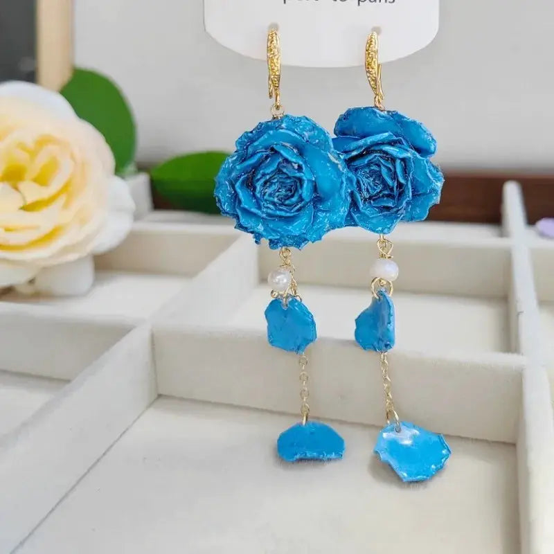 Long blue immortal rose earrings with epoxy resin petals, gold-tone hooks, pearls, and dangling blue resin charms