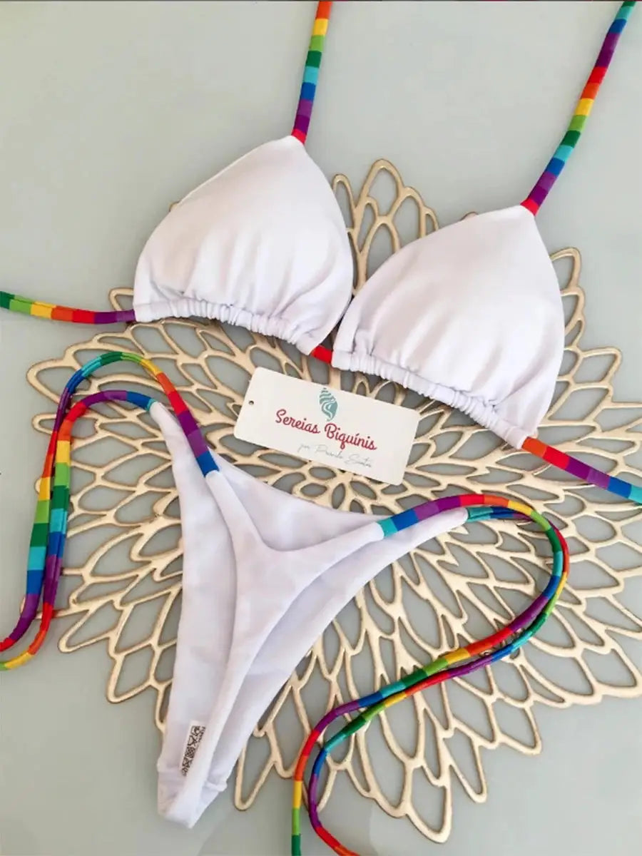 White micro bikini set with rainbow-striped halter top and thong bottoms; Sereias Biquinis tag visible