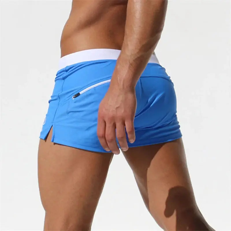 Men's blue quick-drying swim trunks with white waistband and back zip pocket.
