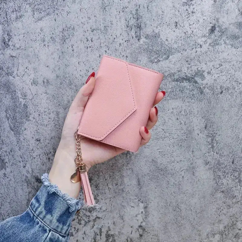 Pink PU leather mini wallet with tassel and chain held in hand