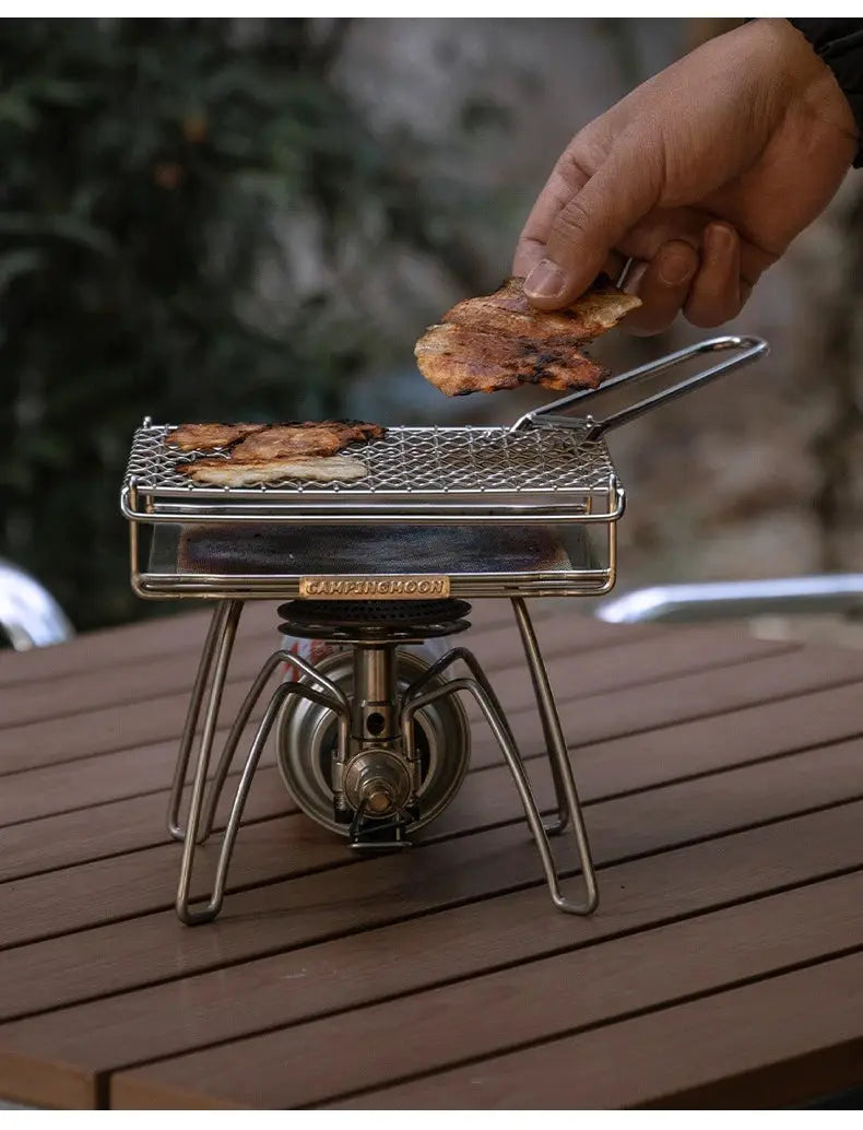 CAMPINGMOON stainless steel folding grill net on a portable gas stove, bacon grilling on the grate.