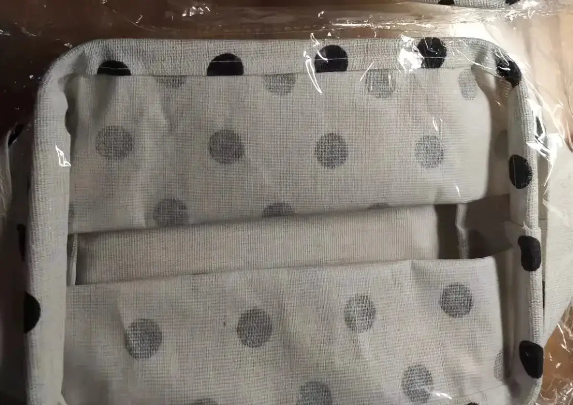 Small foldable canvas storage basket with handle, white fabric featuring gray polka dots for desk organization.
