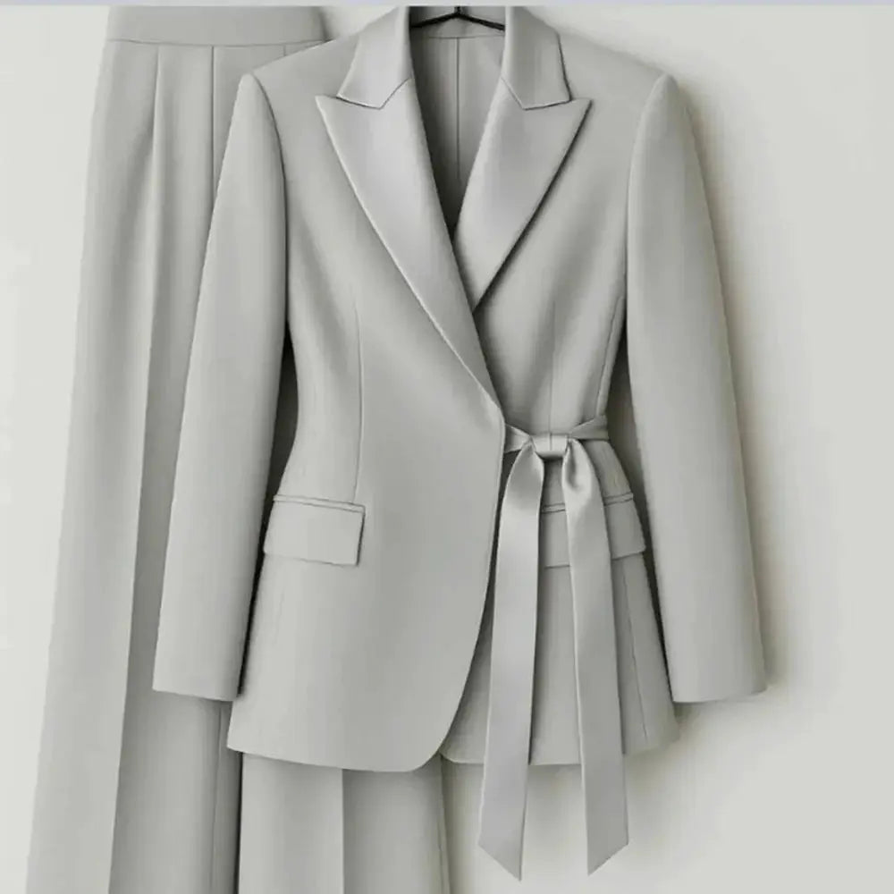 Women's light gray 2-piece suit set featuring belted blazer with peak lapels and matching pants