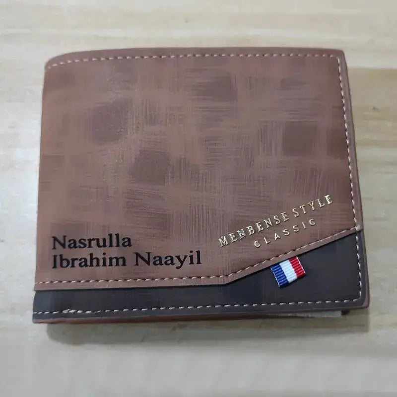 Brown leather men's slim wallet with coin pocket and angled black panel with small flag ribbon